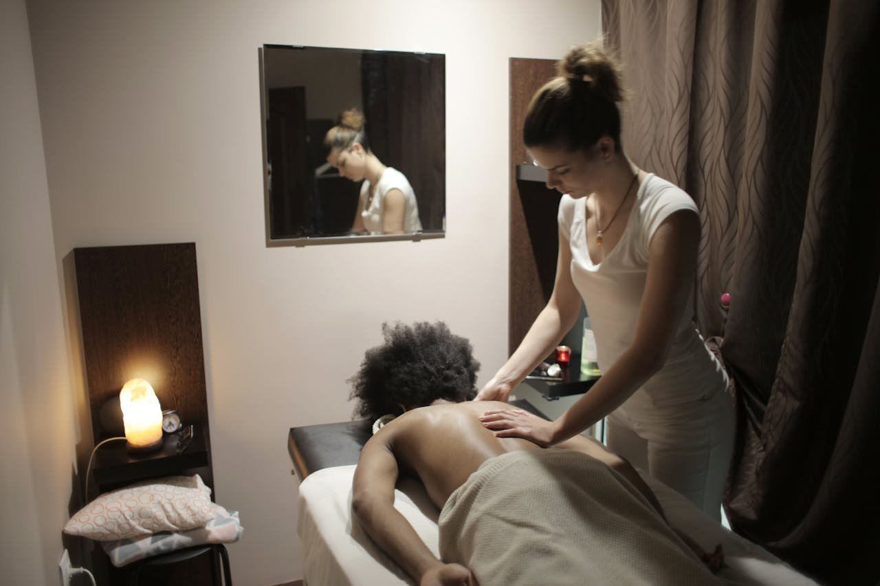 Professional masseuse doing massage of back of client in salon